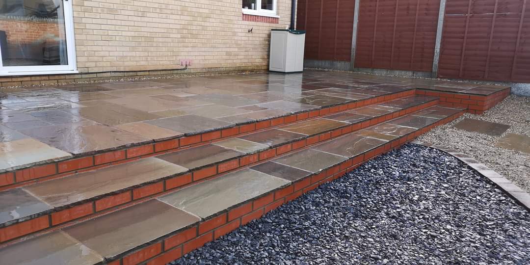 Patio installation Suffolk — Stone slab patio with brick edging and decorative gravel border